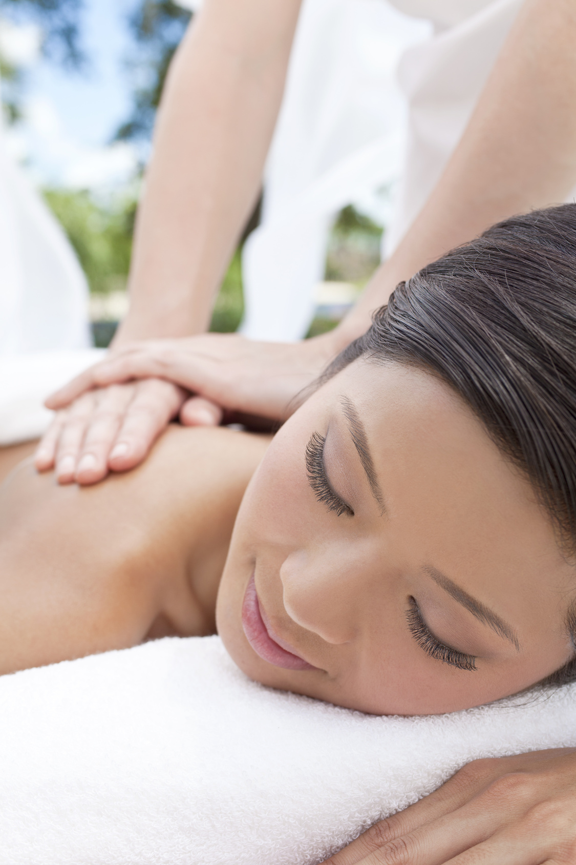 An Asian Chinese woman relaxing outside at a health spa while having a massage outside